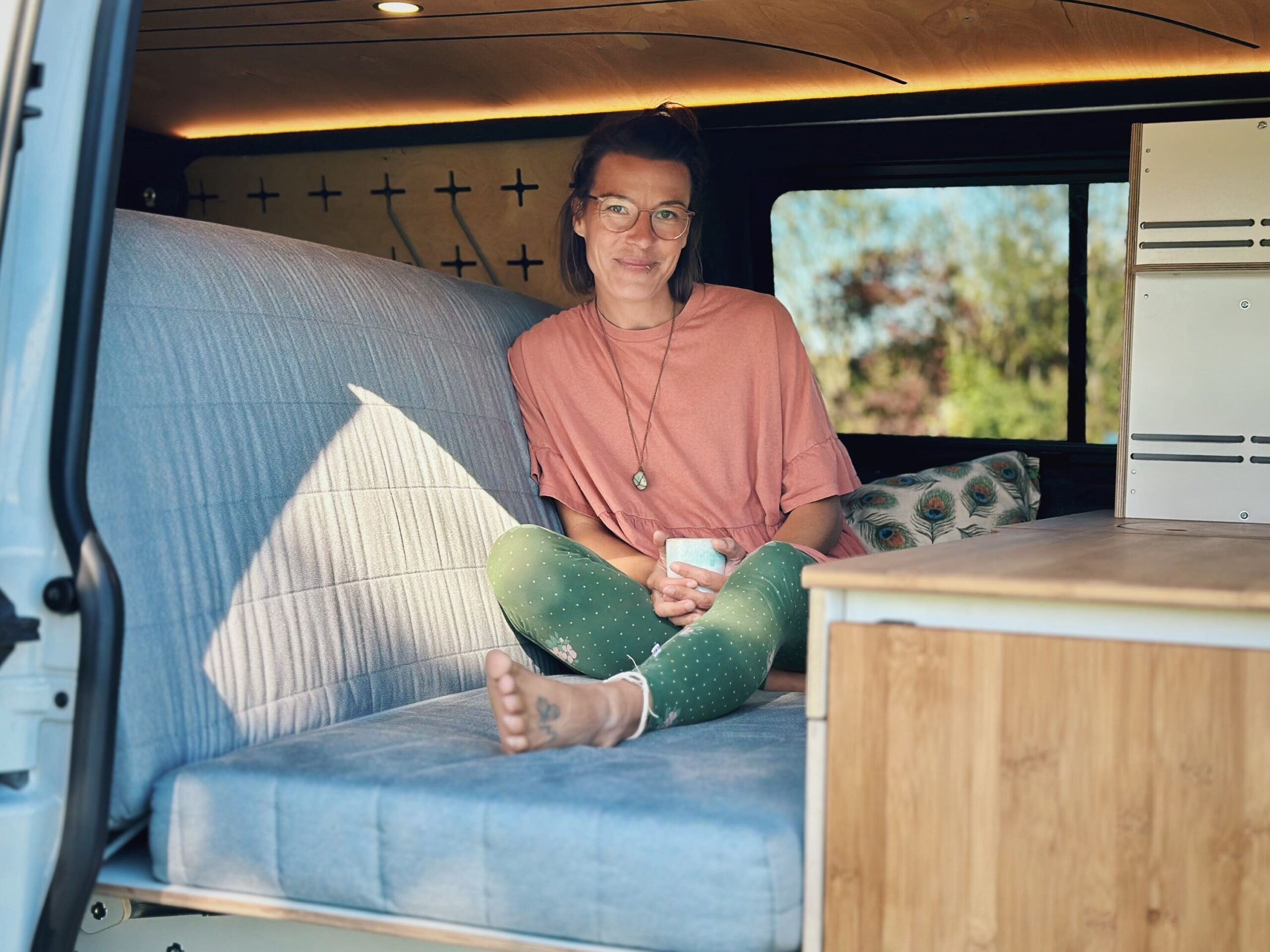 Jedna osoba sedí uvolněně na pohodlném sedadle v kempinkovém vozidle.