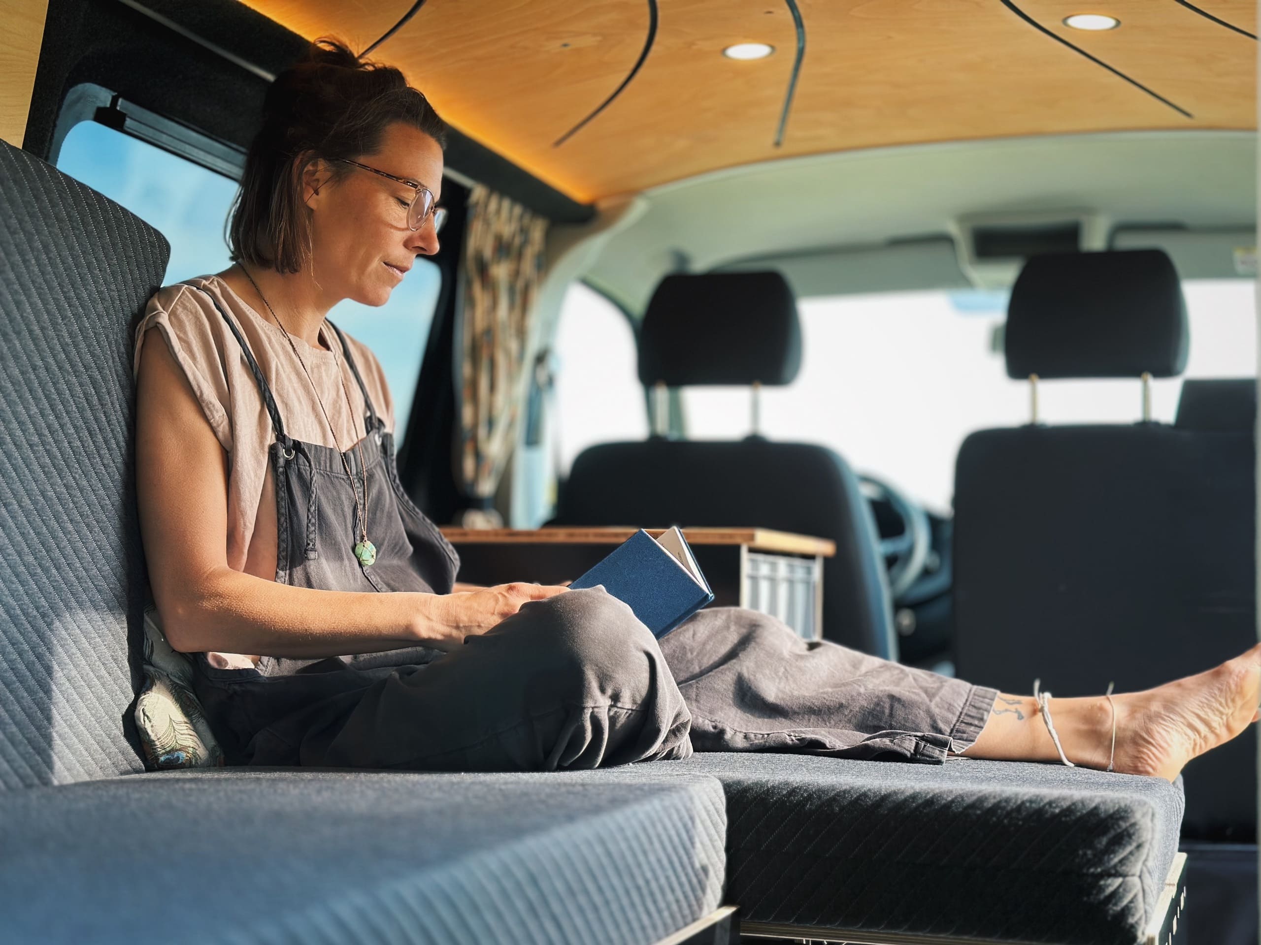 Una persona se sienta relajadamente en una caravana y utiliza un portátil mientras está sentada en un cómodo sistema de descanso.