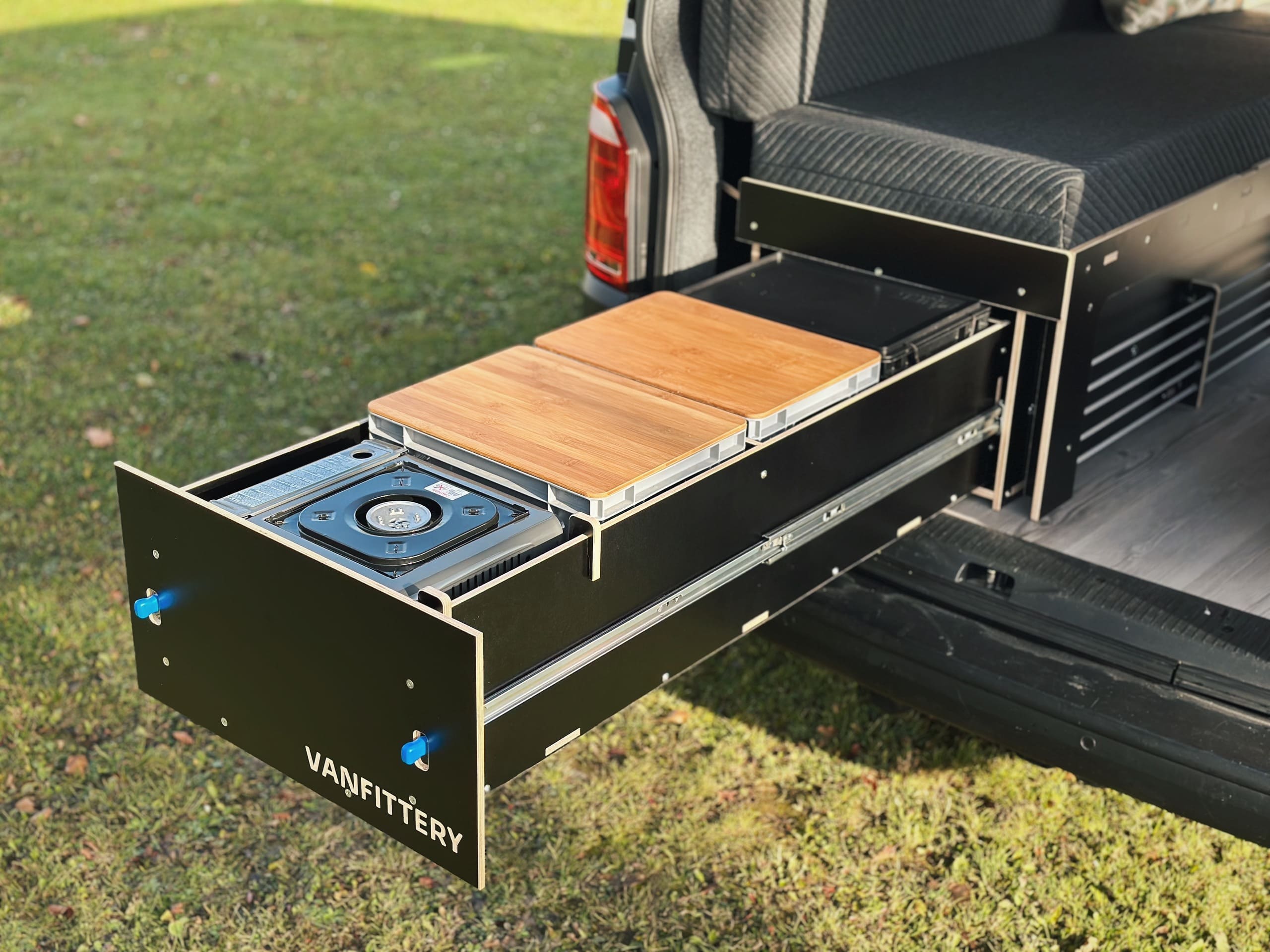 Módulo de camping con cocina extraíble y superficie de madera montado en un vehículo.