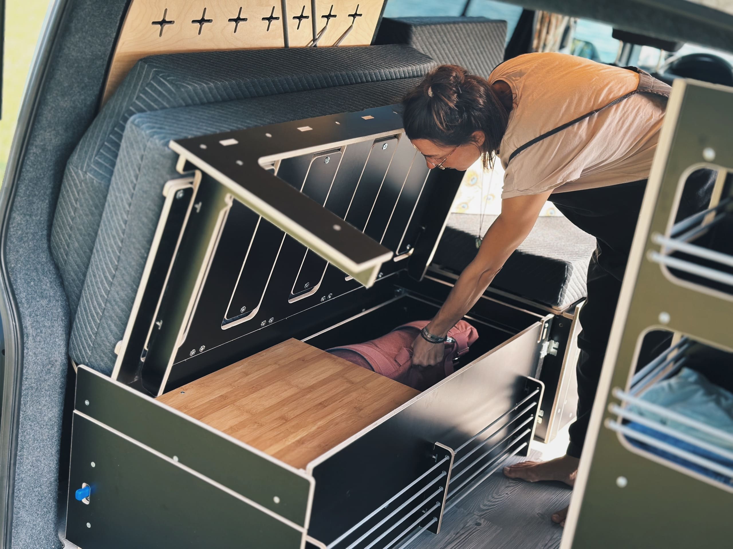 Una persona abre una taquilla de camping modular para guardar un sistema de dormir o accesorios.