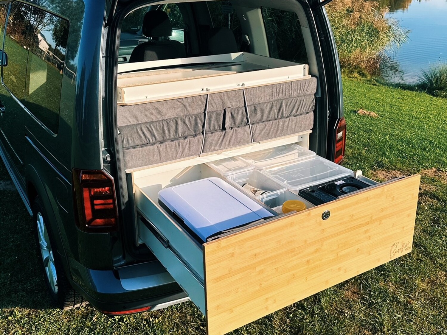 Zdjęcie przedstawia wnętrze pojazdu z rozkładanym modułem kuchennym i systemem spania.