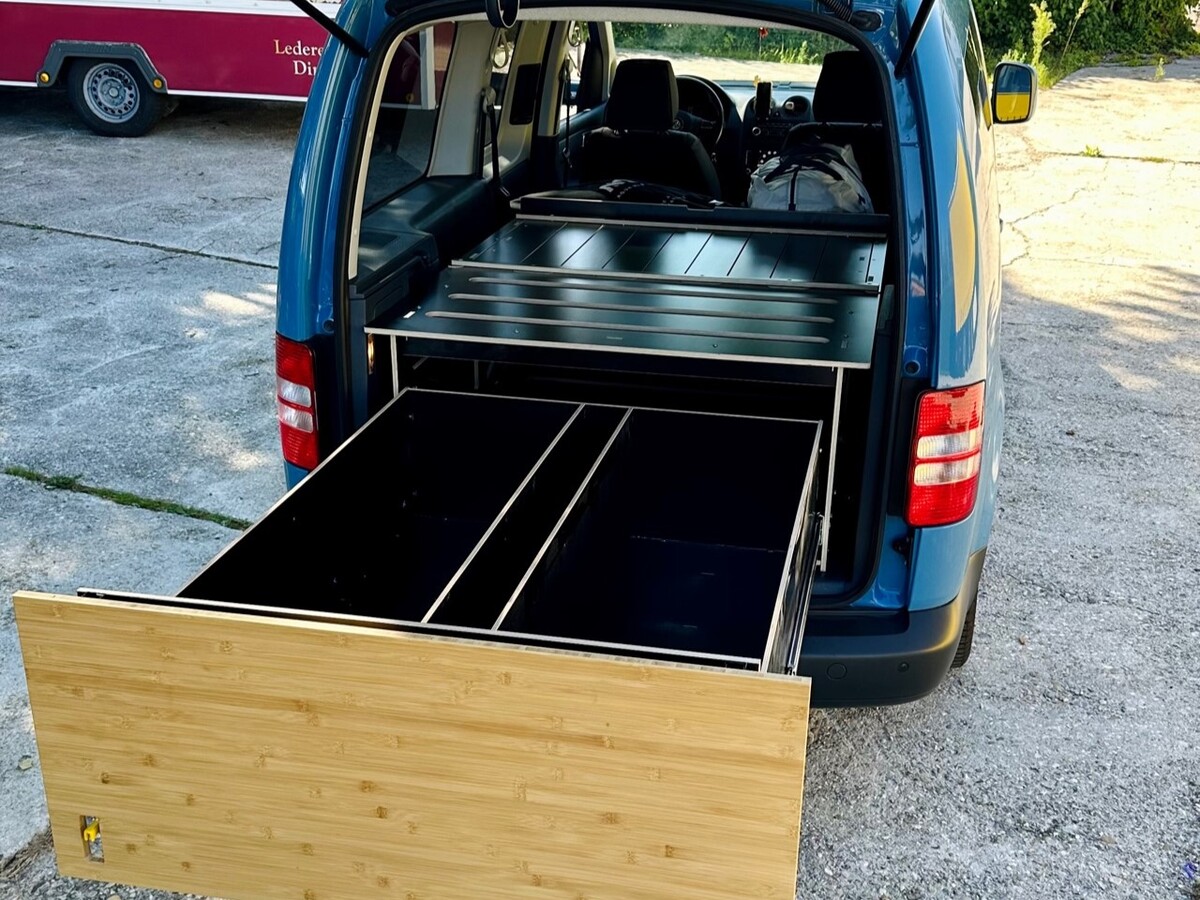 Un camper blu con modulo armadio estraibile in legno e metallo, ideale per organizzare gli accessori e i mobili da campeggio.