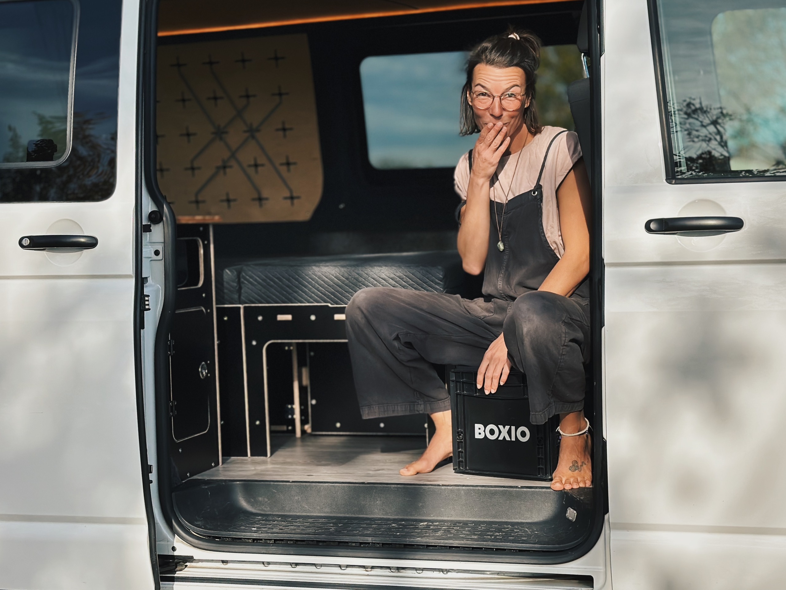 Osoba sedí v kempinkovém vozidle a ukazuje suchou separační toaletu.