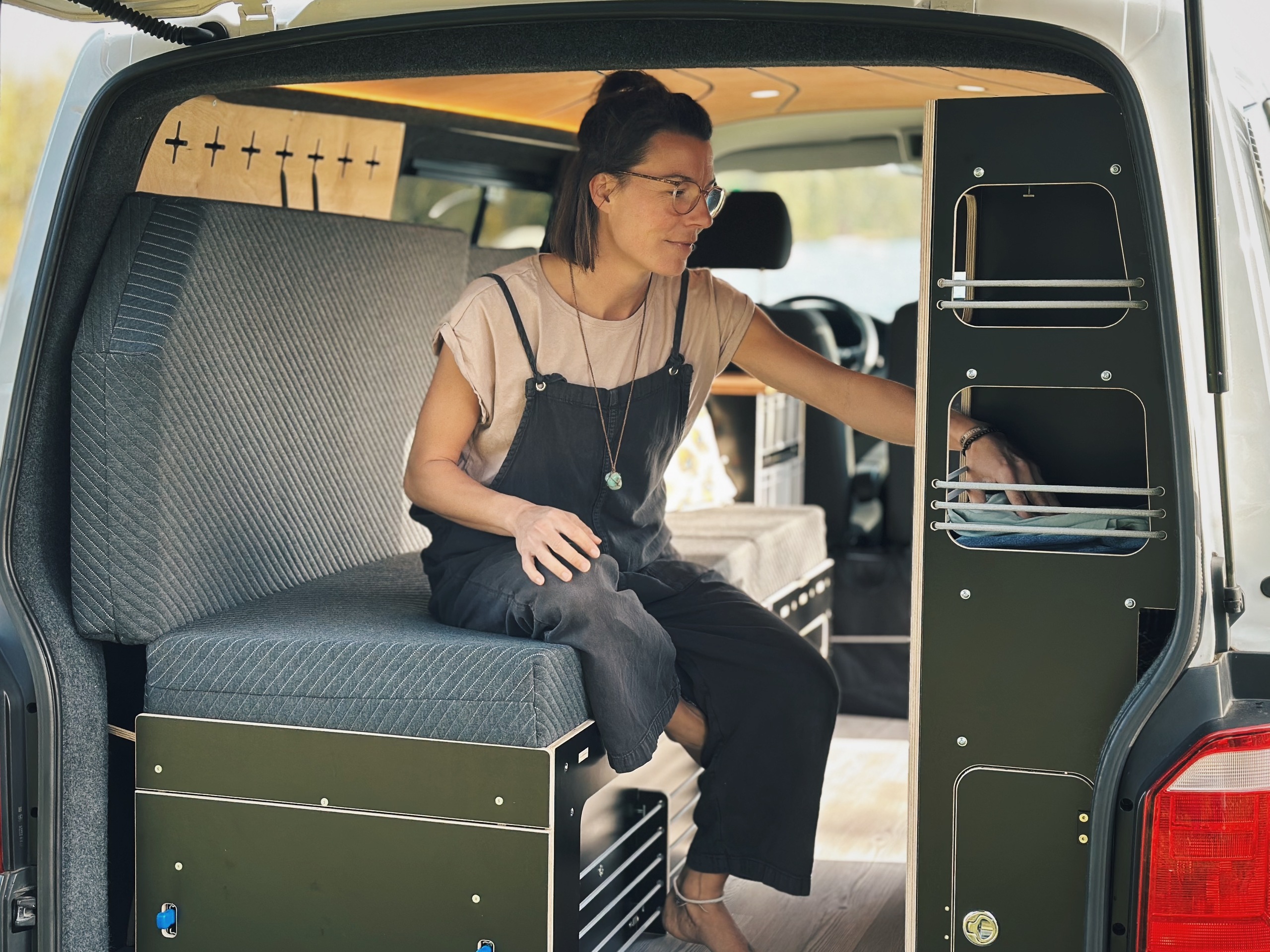 Jedna osoba sedí v obytném vozidle a používá integrovaný nábytek, který je určen pro spací a kuchyňské moduly.