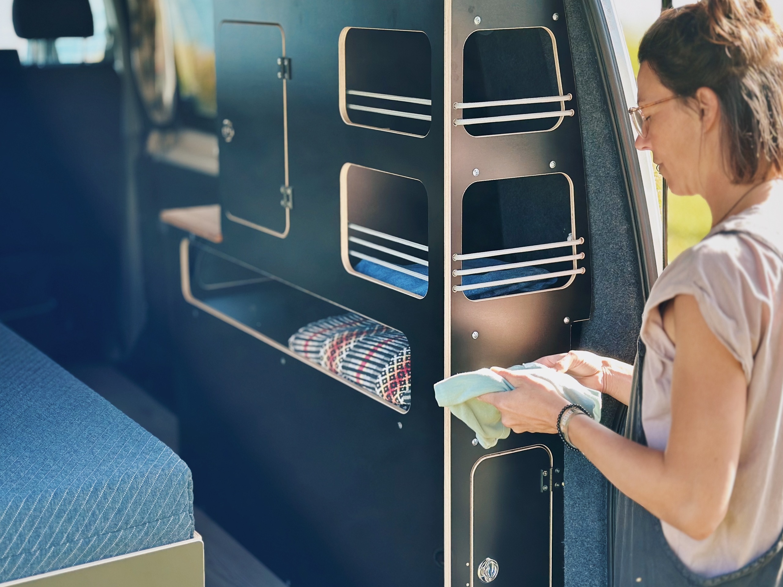 Osoba uspořádá kempinkové příslušenství v modulární skříni ve vozidle vybaveném pro kempování.