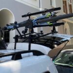 Ein Auto mit einem Fahrradträger auf dem Dach, der zwei Fahrräder sicher befestigt hat, ideal für Campingausflüge und Outdoor-Abenteuer.