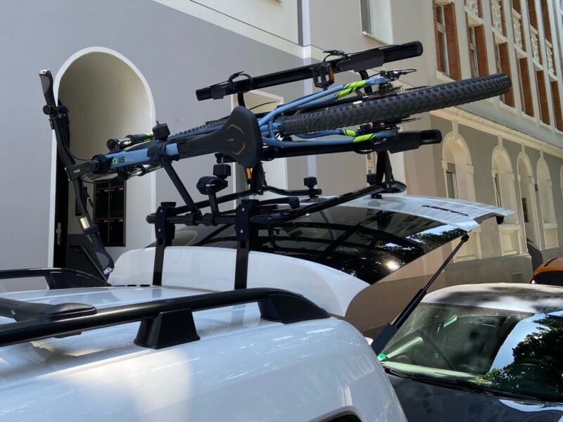 Ein Auto mit einem Fahrradträger auf dem Dach, der zwei Fahrräder sicher befestigt hat, ideal für Campingausflüge und Outdoor-Abenteuer.